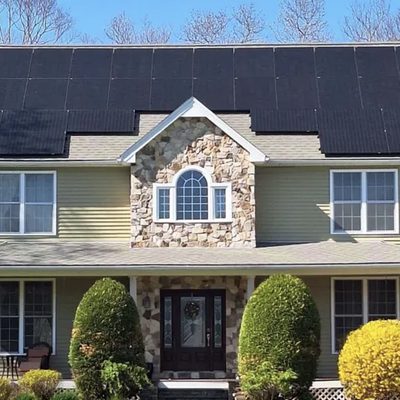 Colonial with a stone front and black solar panels