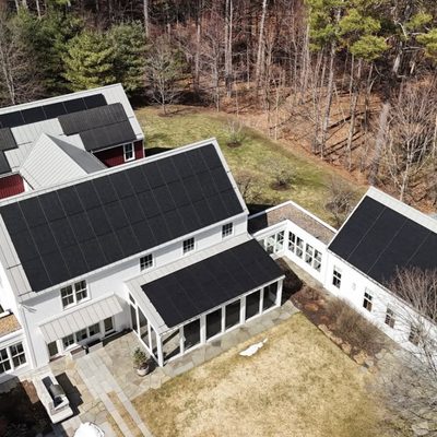 Aerial view of a white house with solar panels on two roofs